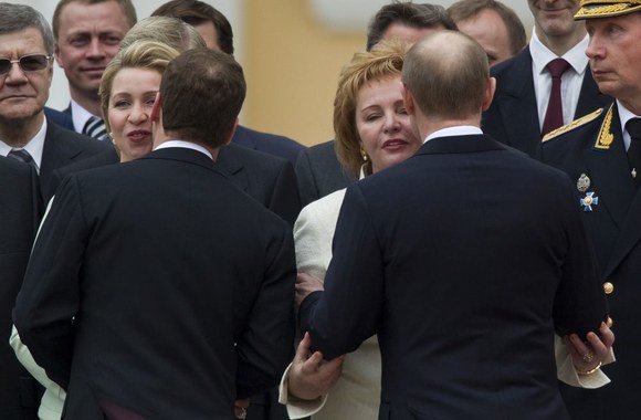 Dmitrijus Medvedevas bučiuoja savo žmoną Svetlaną (kairėje) ir Vladimiras Putinas su žmona Liudmila (kairėje)